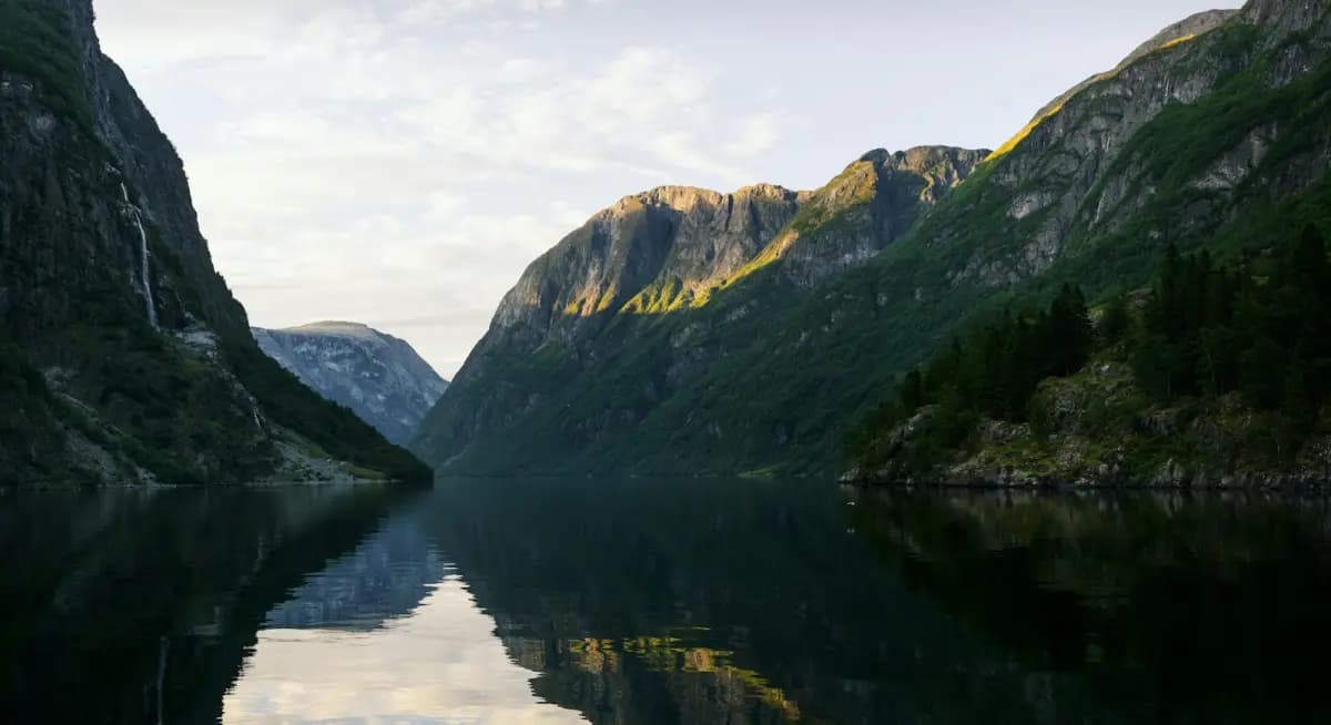 Green mountains reflected in a calm fjord in Geiranger, Norway