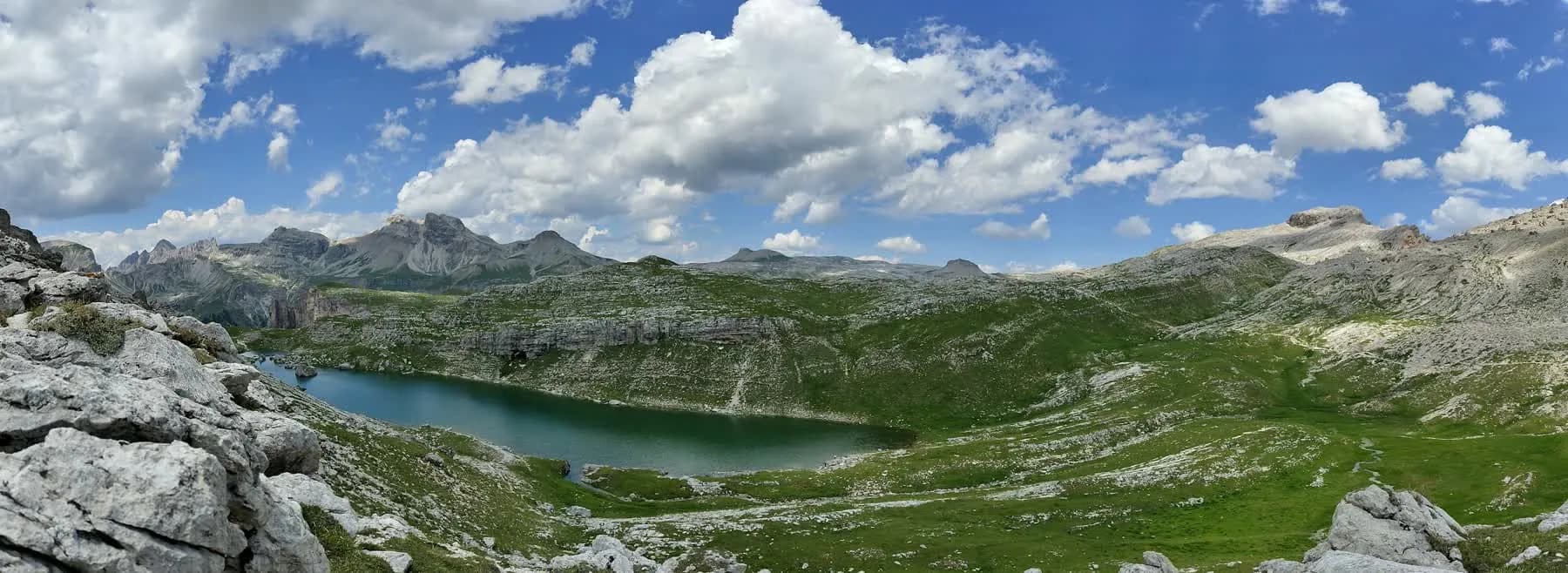 A panoramic view across an alpine lake and the surrounding Dolomite peaks